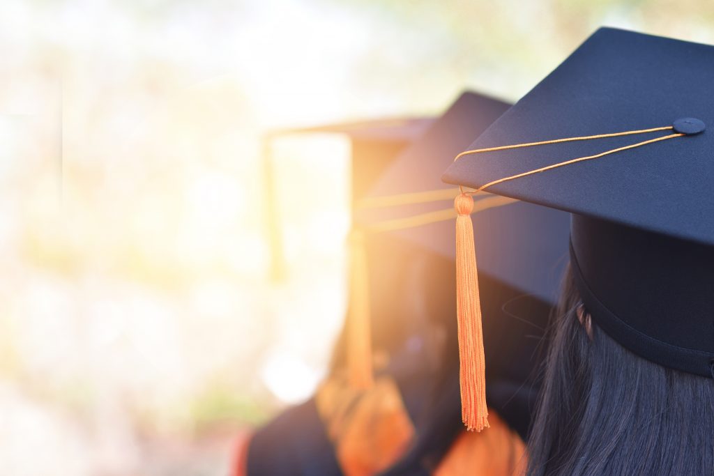 The back image of the graduates wearing a yellow tassel hat.